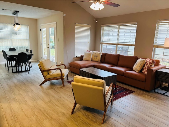 living room with lofted ceiling, ceiling fan, and light wood-type flooring