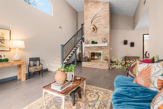 living room with high vaulted ceiling, a fireplace, and hardwood / wood-style floors