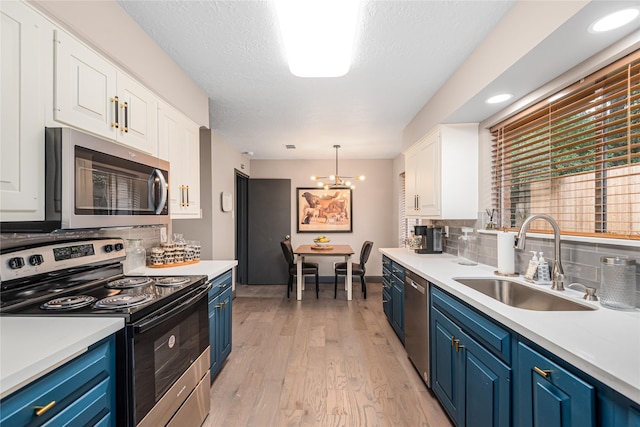 kitchen featuring sink, blue cabinetry, white cabinets, and appliances with stainless steel finishes