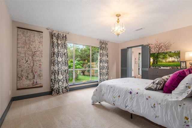 carpeted bedroom with an inviting chandelier and a textured ceiling