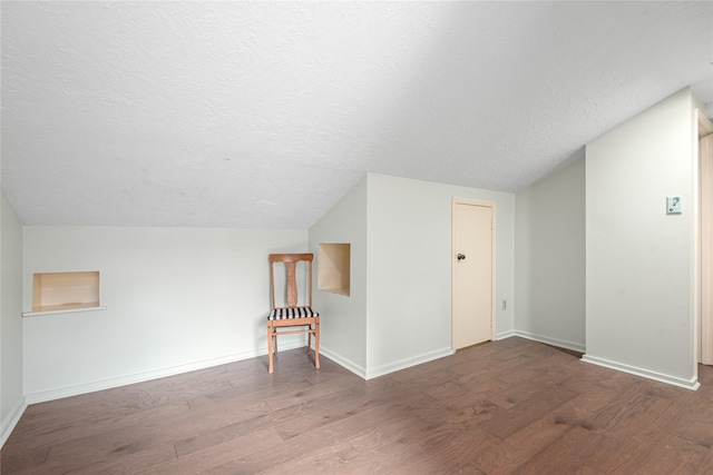 bonus room featuring lofted ceiling, wood-type flooring, and a textured ceiling