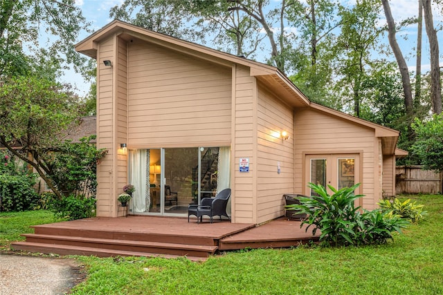 back of property with a wooden deck, a lawn, and french doors