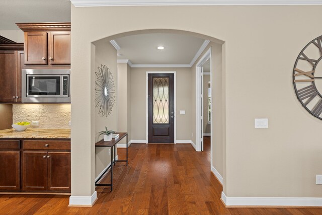 foyer featuring dark wood-type flooring, recessed lighting, crown molding, arched walkways, and baseboards