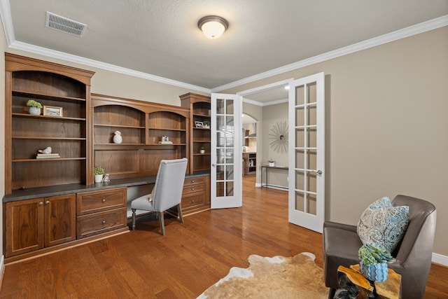 office space featuring built in study area, french doors, dark wood-type flooring, visible vents, and crown molding