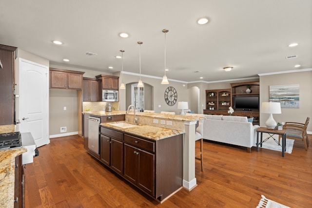 kitchen featuring a sink, stainless steel appliances, a breakfast bar area, visible vents, and arched walkways