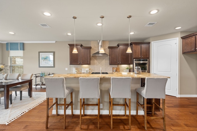 kitchen with stainless steel oven, dark brown cabinets, visible vents, and wall chimney exhaust hood