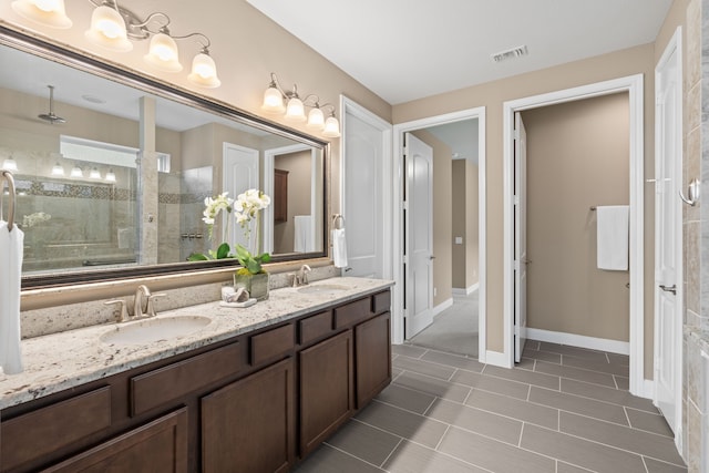 full bath with tiled shower, visible vents, a sink, and double vanity