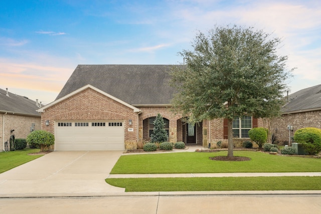 view of front of home with an attached garage, brick siding, driveway, roof with shingles, and a front yard