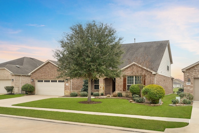 view of front of home featuring an attached garage, brick siding, driveway, and a lawn