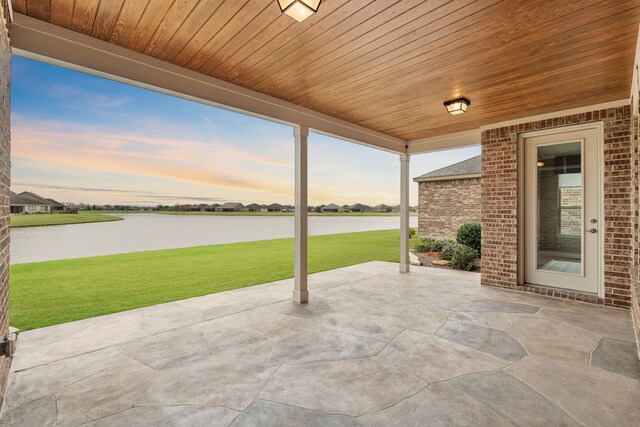 patio terrace at dusk with a yard and a water view