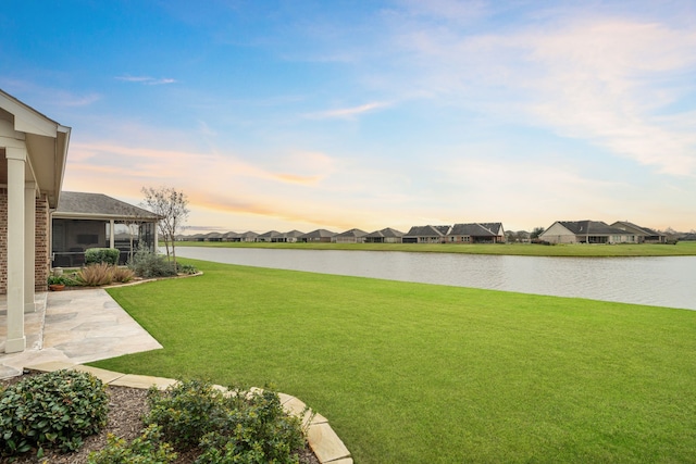 view of yard with a water view, a sunroom, a patio, and a residential view