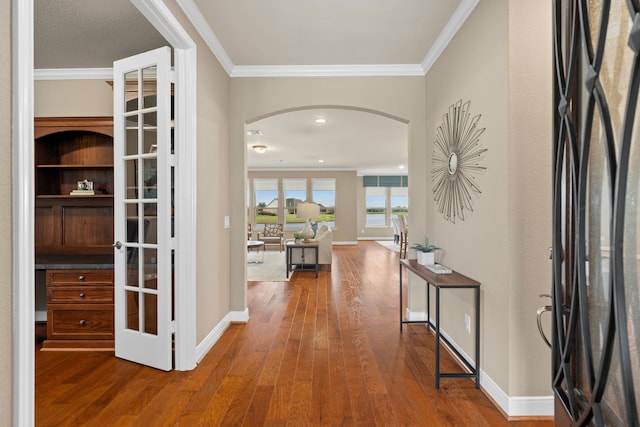 entrance foyer featuring ornamental molding, wood finished floors, baseboards, and arched walkways