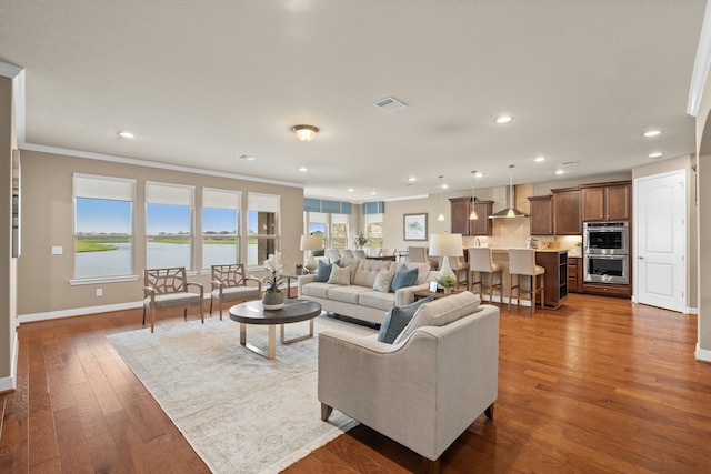 living room featuring dark wood-style flooring, baseboards, visible vents, and recessed lighting