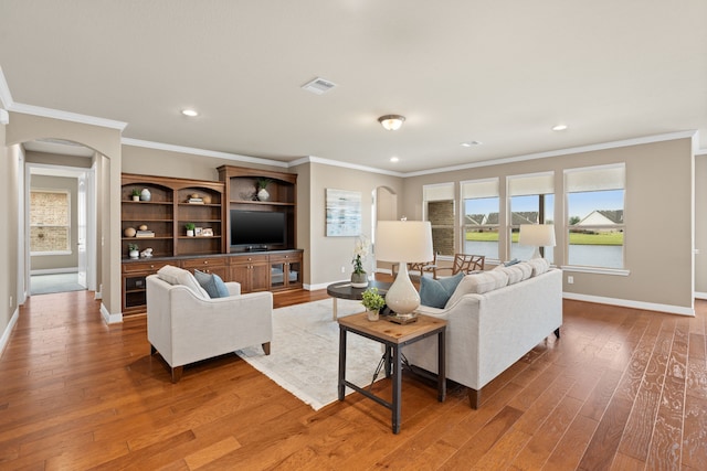 living area with arched walkways, baseboards, and wood finished floors