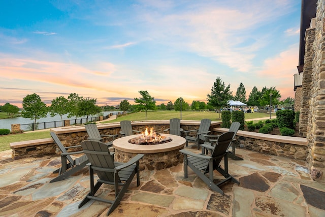 patio terrace at dusk featuring a fire pit and fence