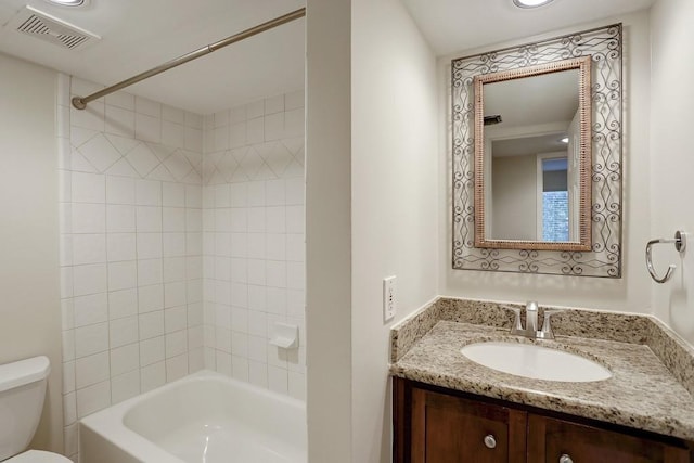 full bathroom featuring tiled shower / bath, vanity, and toilet