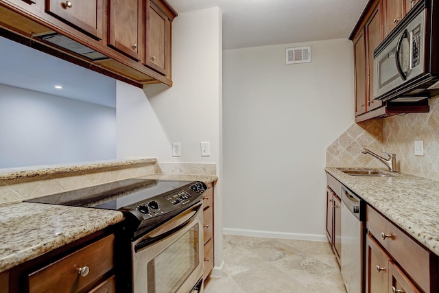 kitchen with light stone counters, sink, decorative backsplash, and appliances with stainless steel finishes