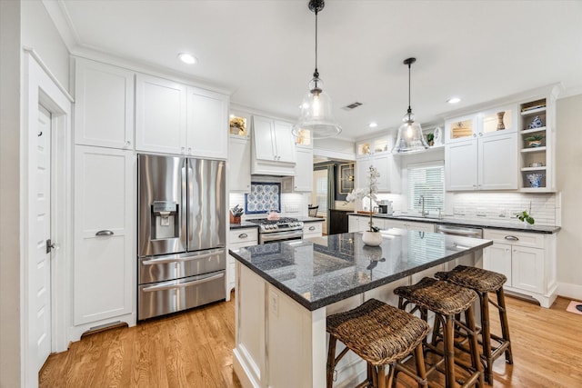 kitchen with a kitchen island, appliances with stainless steel finishes, white cabinets, and a kitchen breakfast bar