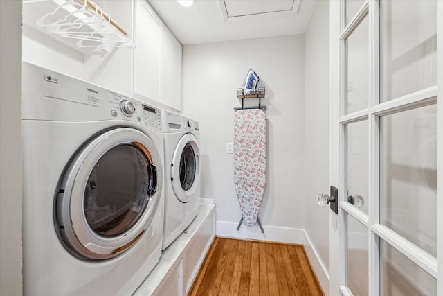 laundry area featuring light hardwood / wood-style floors, cabinets, and washing machine and clothes dryer