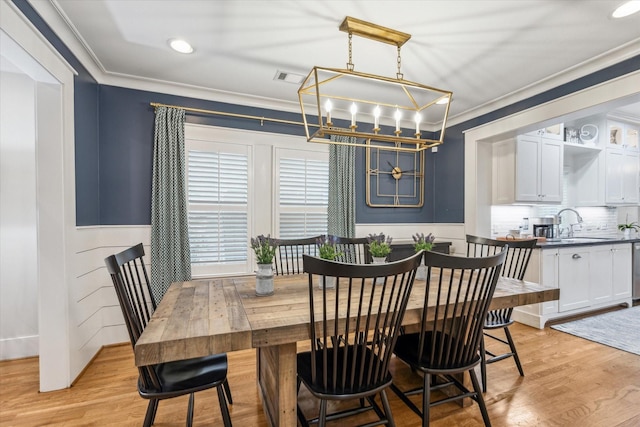 dining area featuring ornamental molding, sink, and light hardwood / wood-style floors