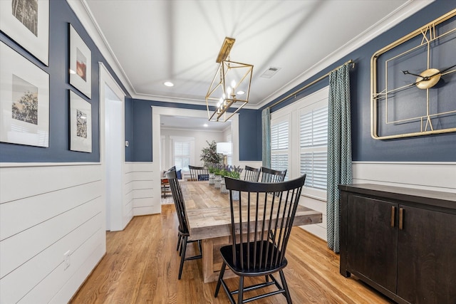 dining space with crown molding, a chandelier, and light wood-type flooring