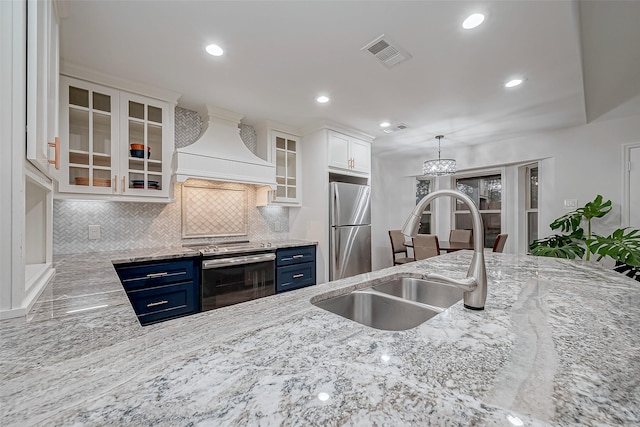 kitchen with sink, premium range hood, stainless steel appliances, white cabinets, and blue cabinets