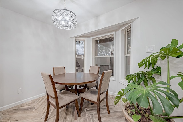 dining area with light parquet floors and an inviting chandelier