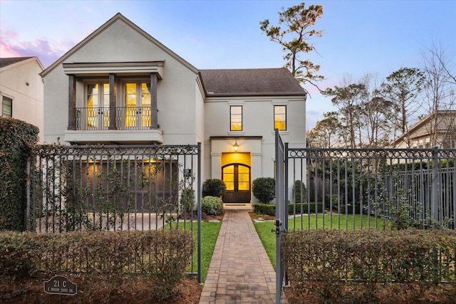 view of front facade featuring a yard, french doors, and a balcony