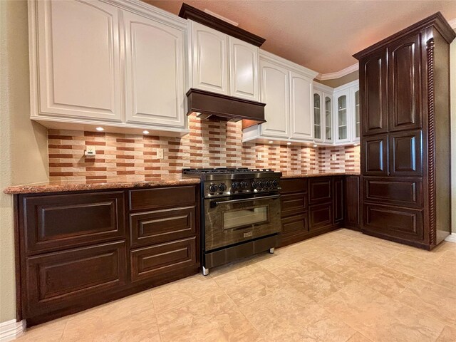 kitchen featuring range with gas stovetop, glass insert cabinets, white cabinets, light stone countertops, and under cabinet range hood