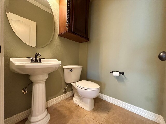 half bathroom with baseboards and toilet