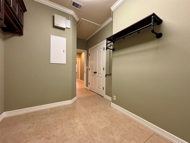 hall featuring crown molding, visible vents, attic access, a textured ceiling, and baseboards