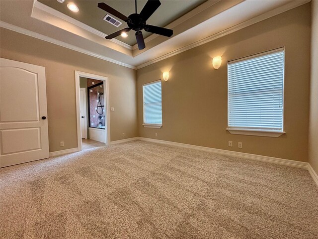 empty room featuring light carpet, visible vents, baseboards, a tray ceiling, and crown molding