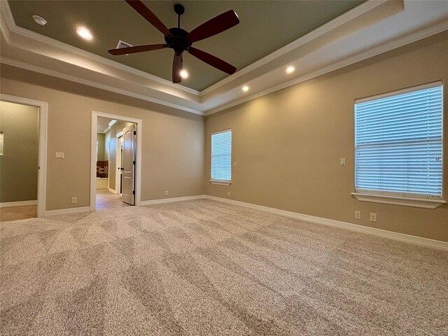 empty room featuring light carpet, recessed lighting, a tray ceiling, and ornamental molding