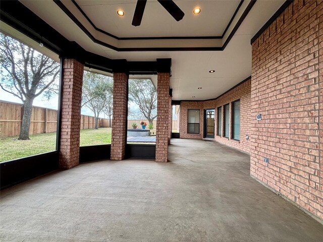 unfurnished sunroom with a tray ceiling and ceiling fan