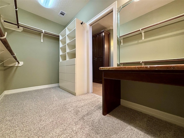 walk in closet featuring light colored carpet