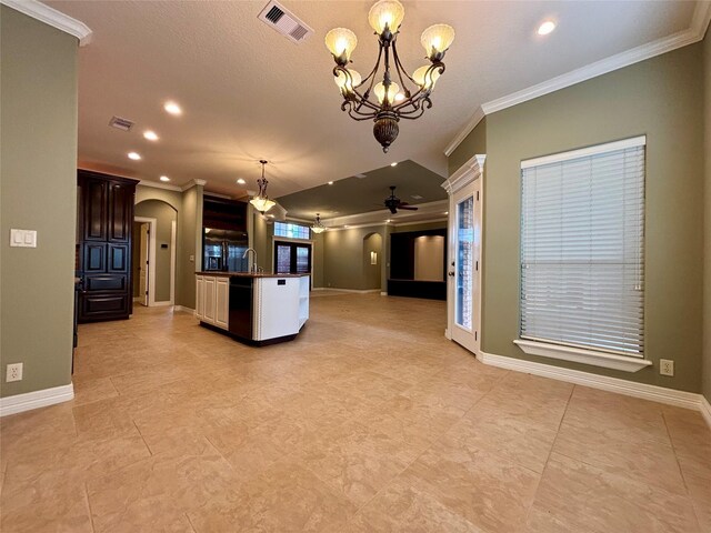 kitchen featuring arched walkways, visible vents, hanging light fixtures, open floor plan, and a sink