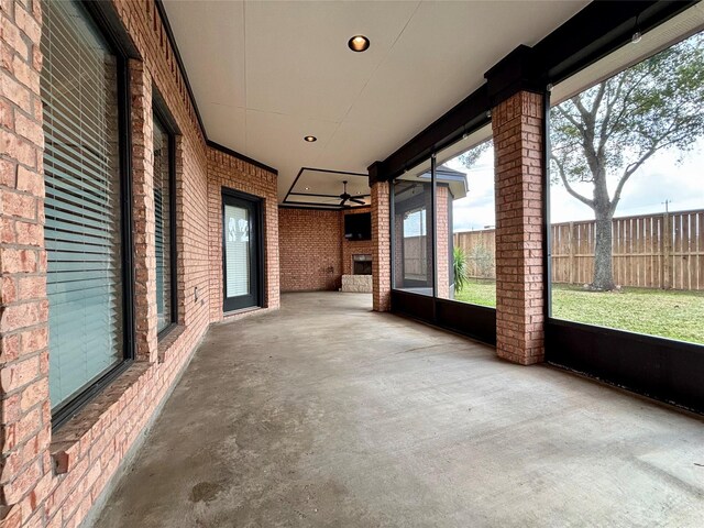 unfurnished sunroom with ceiling fan and a fireplace