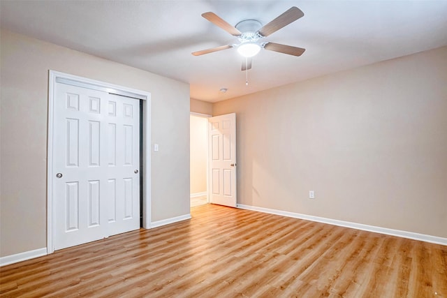 unfurnished bedroom featuring ceiling fan, a closet, and light wood-type flooring