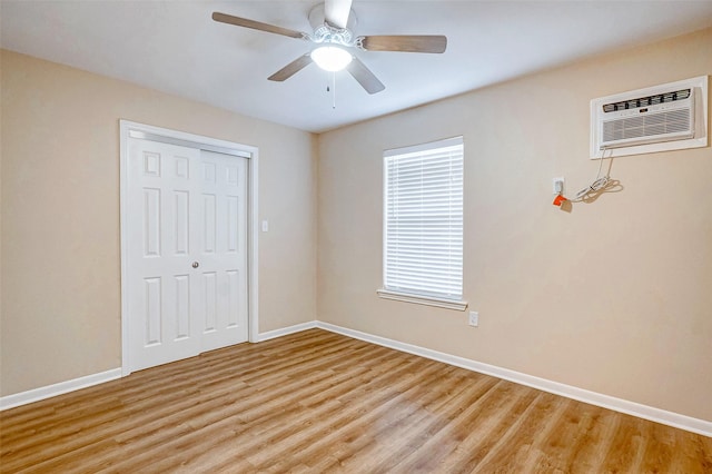 unfurnished bedroom featuring a closet, light hardwood / wood-style floors, an AC wall unit, and ceiling fan