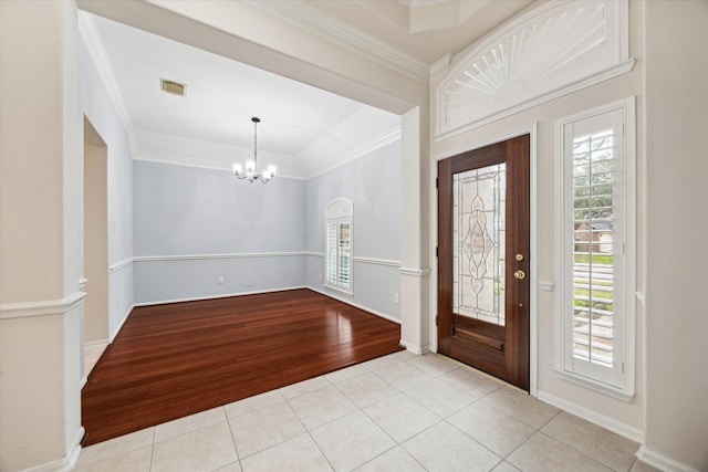 entryway featuring tile patterned flooring, a notable chandelier, visible vents, baseboards, and crown molding