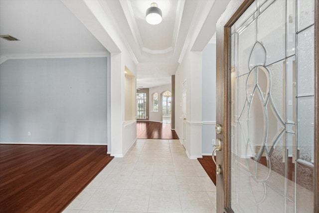 hall with light tile patterned floors, baseboards, visible vents, and ornamental molding