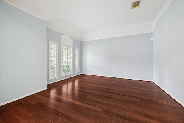 empty room with baseboards, wood finished floors, visible vents, and crown molding