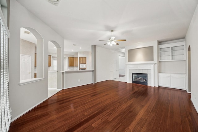 unfurnished living room featuring visible vents, ceiling fan, a tiled fireplace, and wood finished floors