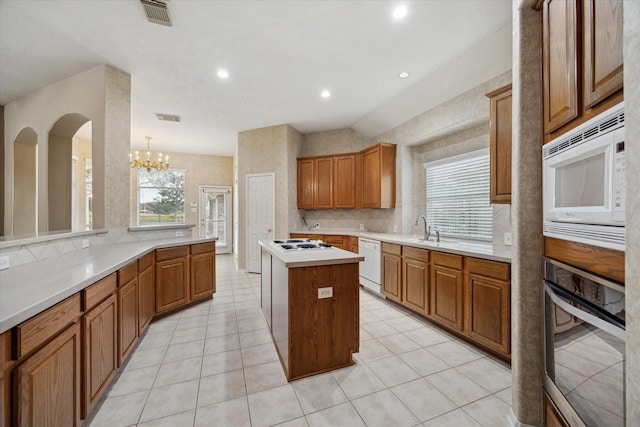 kitchen featuring white appliances, light tile patterned floors, visible vents, a center island, and light countertops