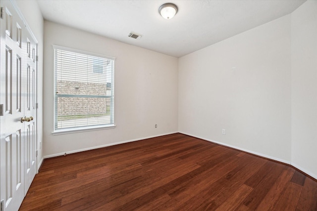 empty room with baseboards, visible vents, and wood finished floors