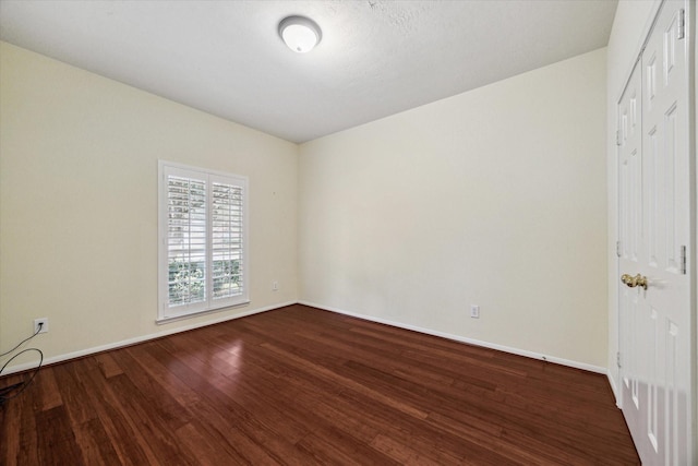 unfurnished room featuring dark wood-style floors and baseboards