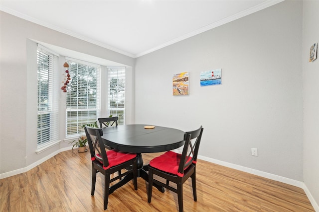 dining space with ornamental molding and light hardwood / wood-style floors