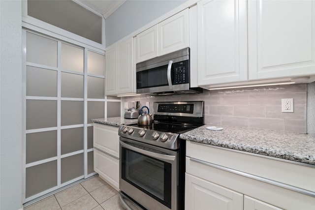 kitchen with white cabinets, appliances with stainless steel finishes, light tile patterned floors, and backsplash