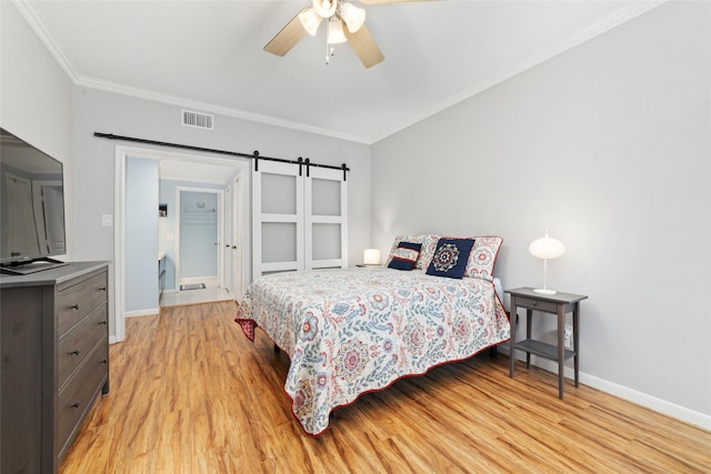 bedroom with ceiling fan, ornamental molding, a barn door, and light hardwood / wood-style floors