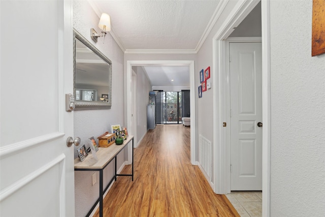 hall featuring ornamental molding, a textured ceiling, and light wood-type flooring